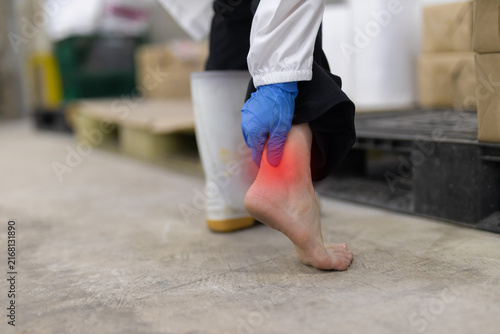 Canvas Print Factory worker holding painful inflamed ankle suffering severe injury wearing wh