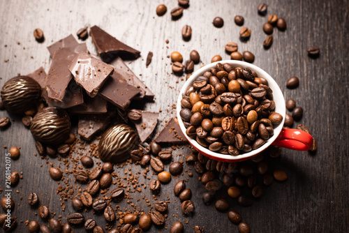 Foto Chocolate pieces and a red cup of coffee beans on a dark surface, minimalist sti