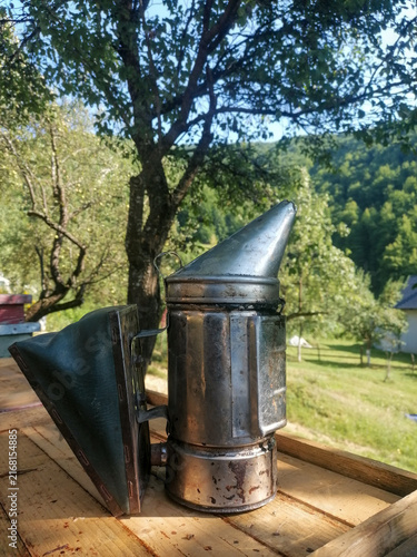 Fotografía Traditional stainless steel bee smoker tool on a wooden beehive box