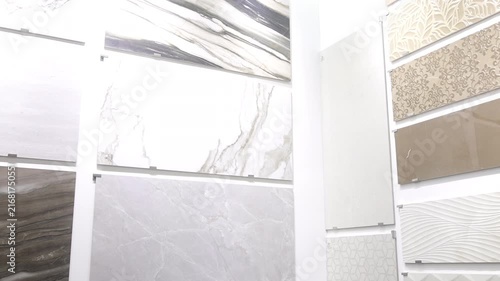Showroom display of large tile panels with varied marble, stone, and decorative relief finishes under bright overhead lighting, with tile, showroom, marble, stone detail