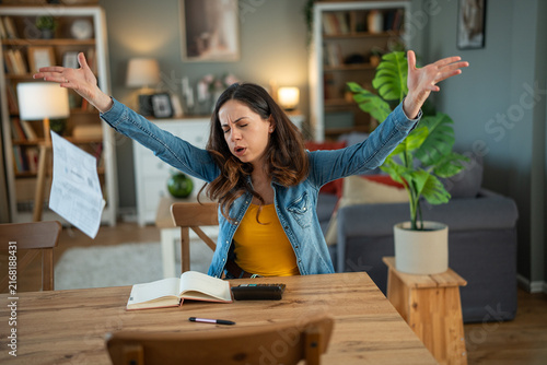 Foto Young woman frustrated by financial problems throwing bills