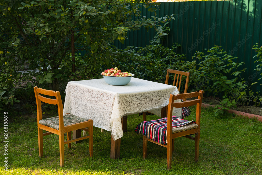 Fototapeta premium Apple harvest with a garden table and chairs in a lush outdoor garden 