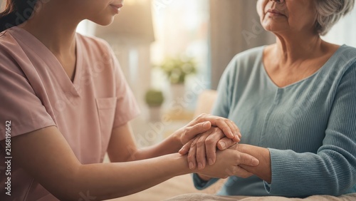 Young caregiver holding elderly woman hand and offering emotional support at home