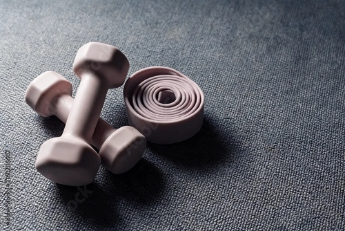 Pastel Light Dumbbells And Coiled Resistance Band On Soft Grey Exercise Mat For Home Strength