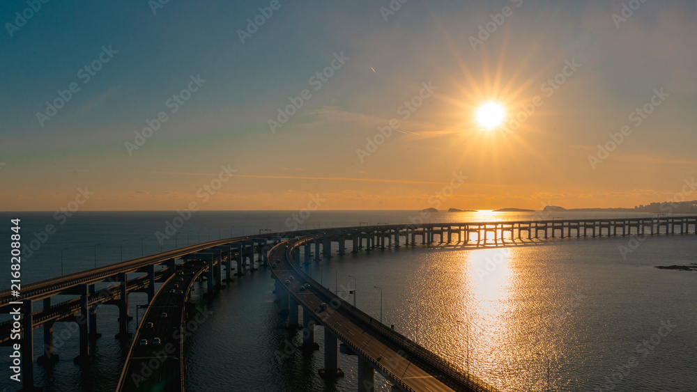 Fototapeta premium Panoramic view of an aerial suspension highway curving over the ocean at dusk