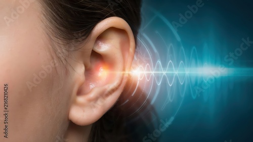 A glowing sound wave digital interface visualizes data entering a human ear. This represents advanced medical technology or audio communication concepts.