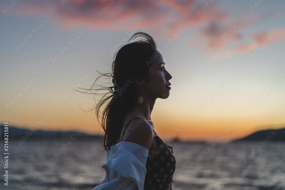 Fototapeta premium 夕暮れの海にいる女性
