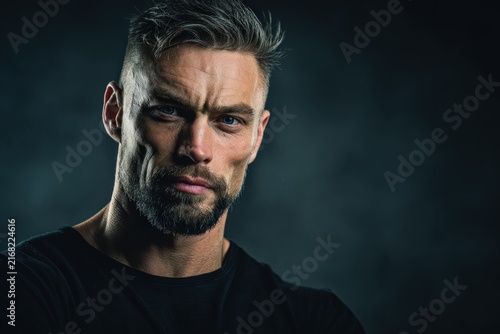 Man shows confidence with strong expression against dark background and shadows