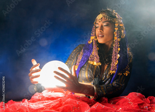 A South Asian woman dressed as a mystical figure holds a glowing