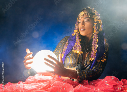 A fortune teller South Asian woman holds a glowing crystal ball