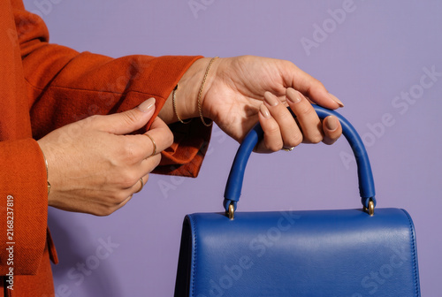 Woman Holding Blue Handbag With Nude Manicure and Gold Jewelry