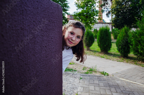 Student looks around a corner of the school as she gets ready for the school year. She smiles and appears curious