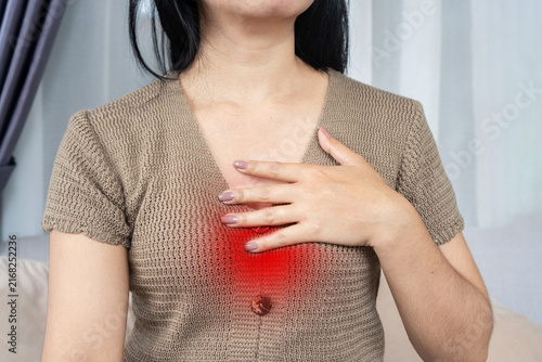 Quadro su tela Asian woman touching her chest suffering from heartburn, acid reflux, GERD, and chest pain with red highlighted area