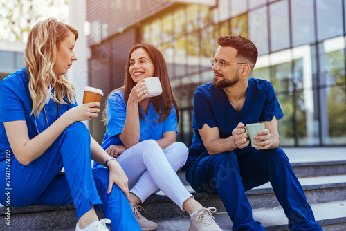 Smiling Nurses and Healthcare Team Enjoying Coffee Break Outside Modern Hospital Building