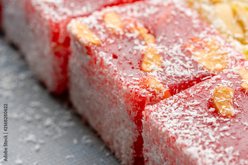 Fototapeta premium Assorted Turkish delight sweets pattern background. Colorful Rahat lokum with nuts and coconut flakes close up. Dessert