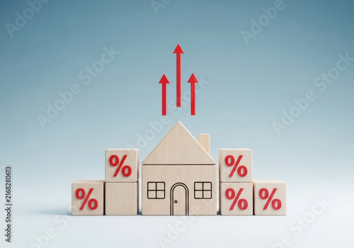 Wooden toy house surrounded by percentage cubes under rising red arrows representing increasing mortgage interest rates and cost.