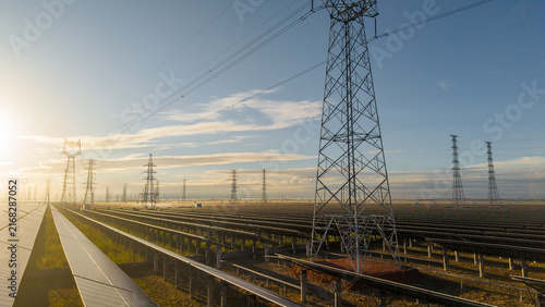 Solar Power Farm With Transmission Towers At Sunrise