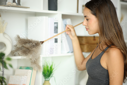 Fotografía Woman at home cleaning furniture with duster