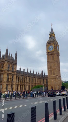 Crowds of tourists walking near Big Ben and the Palace of Westminster with nearby road traffic. Scene of everyday city life and sightseeing in central London