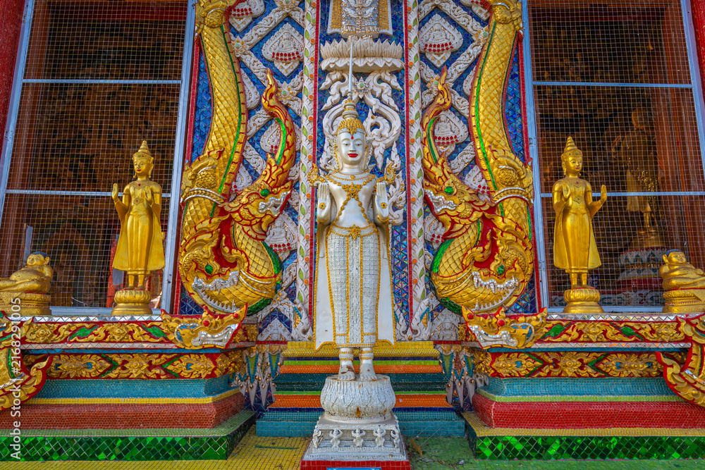 Fototapeta premium White standing angel statue flanked by golden Buddha figures and Naga serpents at Wat Sri Uthumphon in Mueang Nakhon Sawan District, Nakhon Sawan, Thailand, showcasing ornate Thai art facade.