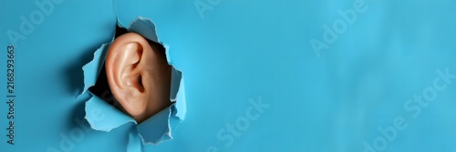 Curious human ear peeking through a torn hole in vibrant blue paper, symbolizing listening and secrets