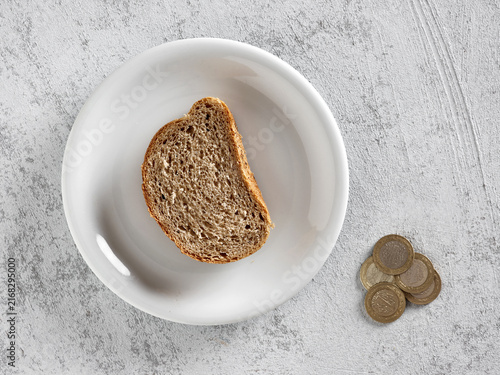 Foto Bread slice on plate with coins representing poverty