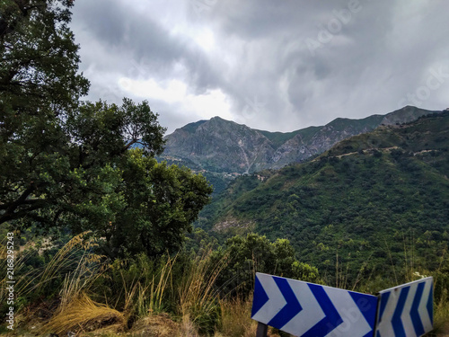 Foto Mountainous landscape featuring lush green peaks under dramatic overcast skies w