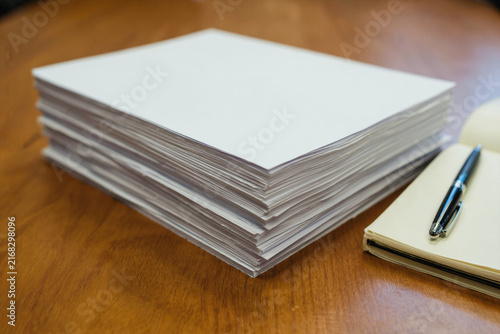 Stack of Blank White Paper and Notebook on Wooden Table