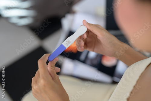 Bild auf Leinwand A person holds and examines a positive pregnancy test showing two lines, indicating pregnancy
