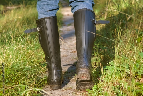 Принти на полотні Person wearing black rubber wellington boots hiking on a muddy forest path part 2