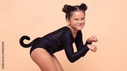 Playful girl in black cat costume crouching with tail and whiskers