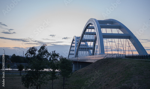 Modern white arch bridge over river at twilight in Novi Sad