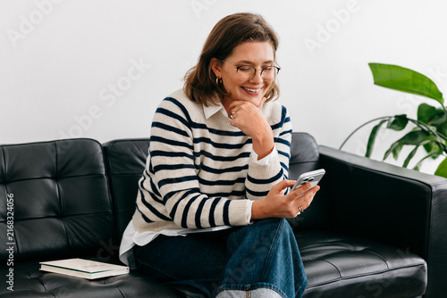 Communication shapes how the woman works from home on a couch with a smartphone