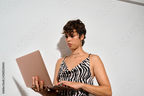 Standing Businesswoman working at Office. DIrect flash shot. She types intently on her laptop
