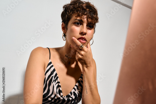 Businesswoman working at Office. DIrect flash shot. She pauses thoughtfully, hand near her chin, eyes focused. Intense concentration mixed with quiet confidence.