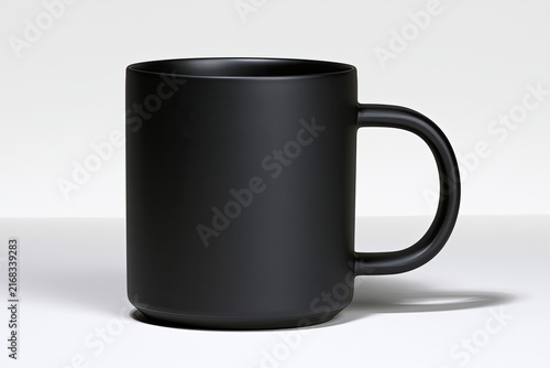 A minimalist, matte black ceramic mug with a simple handle on a white surface