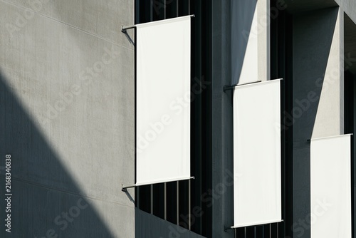 Stark concrete facade with three blank white banners in sunlight