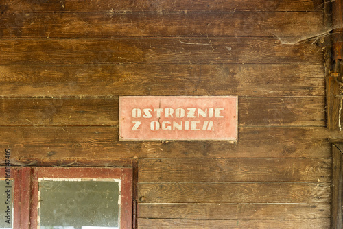 Принти на полотні Vintage Polish fire safety sign reading “Be careful with fire” mounted on a weathered wooden wall with cobwebs and an old window