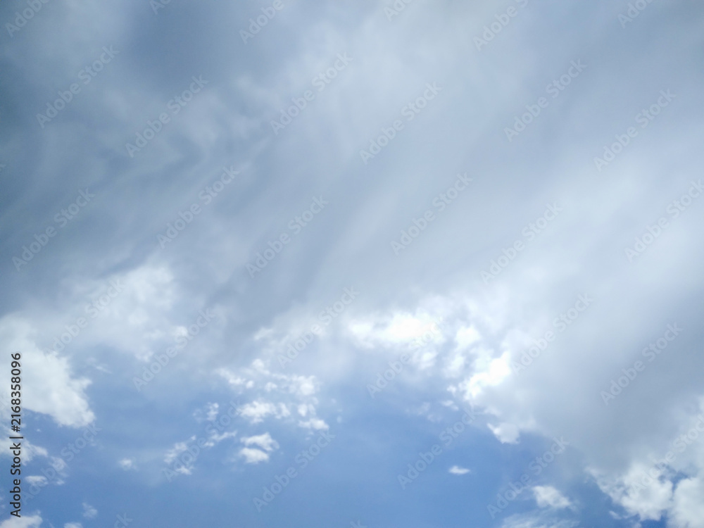Obraz premium Blue sky filled with thick white and grey storm clouds captured during a bright summer afternoon looking upwards towards the high vast infinite atmospheric space