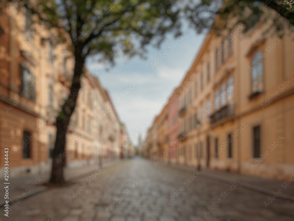 Fototapeta premium Blur image of a quiet city street with classic facades and greenery, suitable for architecture, tourism, urban lifestyle, and travel concepts.