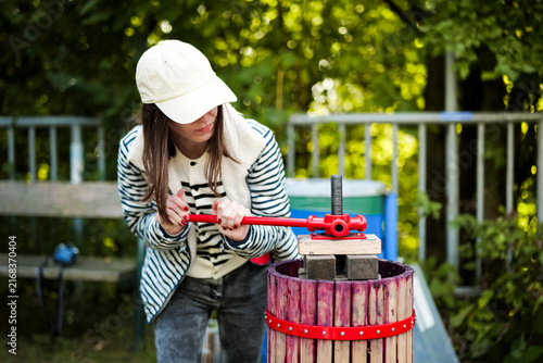 Photography Woman turning a manual fruit press with visible effort during a sustainable winemaking workshop, highlight regional techniques