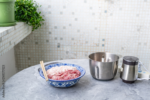 Foto Preparing minced pork: a bowl of fresh pork and a meat grinder.
