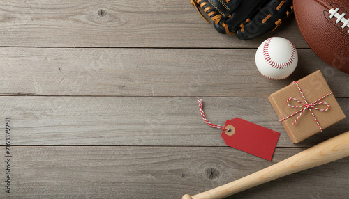 Sports equipment with gift box and tag on wooden background