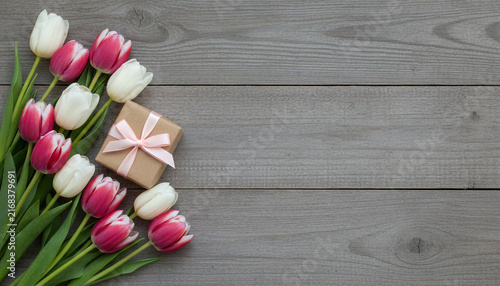 Gift box with tulips on a gray wooden background
