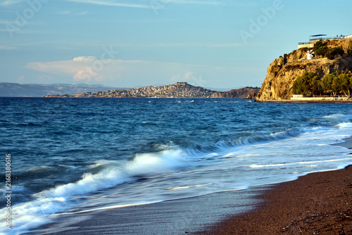Foto pebbly beach with umbrellas, windmill on a rock and view of Molyvos village on L