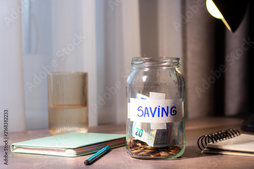 Future planning with long term savings jar. Hand adding substantial savings to future security container. Financial planning and safety concepts
