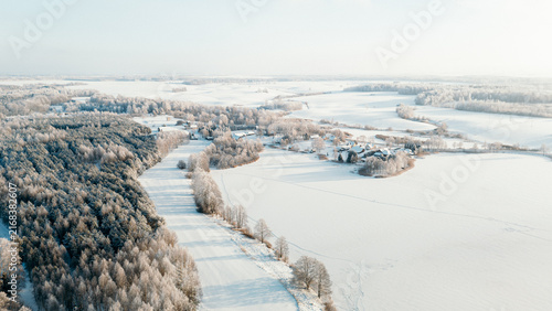 Wide aerial view of a snow-covered river valley with a frozen river and village houses, lithuania winter travel content, rural tourism marketing, christmas card background, winter landscape photo
