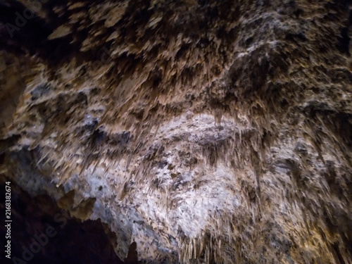 Quadro su tela Jagged limestone stalactites hanging from a dark cavern ceiling captured in shar