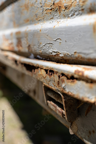 фотографія Severe rust corrosion and peeling paint on metal truck body edge with latch component, showing metal decay, surface deterioration, and material wear
