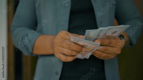 Man investor counting US Dollar bills, close-up. Male trader holds bundle of money, Considers USD at home. Person manages budget.